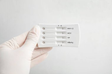 Eldivenli doktor, beyaz arka planda hepatit için tek kullanımlık ekspres test tutuyor.