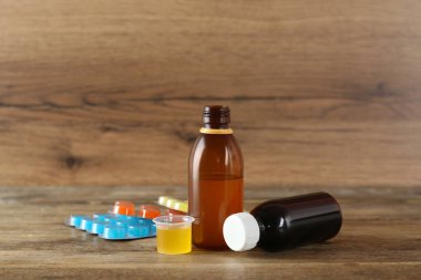 Öksürük şurubu ve ahşap masada pastiller.