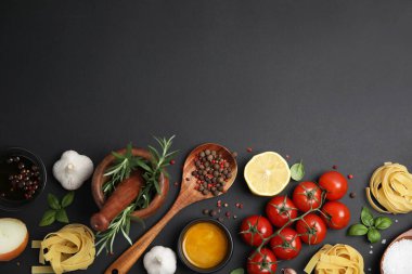 Flat lay composition with cooking utensils and fresh ingredients on black background. Space for text