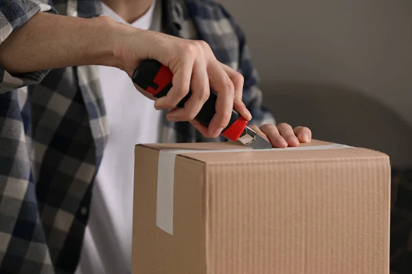 Man Använder Verktygskniv För Att Öppna Paket Inomhus Närbild — Stockfoto