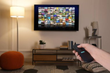 Uzaktan kumandalı kadın evde televizyon izlerken kanal değiştiriyor, kapatıyor