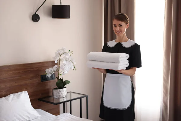 宾馆房间里有一堆堆新鲜毛巾的漂亮女服务员 — 图库照片
