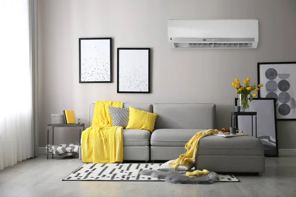 带有时髦沙发的客厅浅灰墙上的现代空调机 — 图库照片