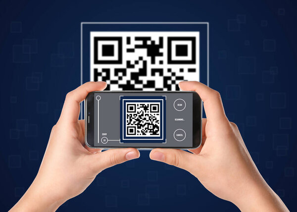 Woman scanning QR code with smartphone on dark blue background, closeup