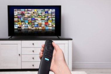 Uzaktan kumandalı kadın evde televizyon izlerken kanal değiştiriyor, kapatıyor