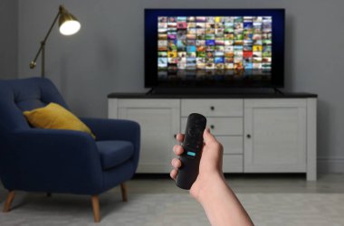 Uzaktan kumandalı kadın evde televizyon izlerken kanal değiştiriyor, kapatıyor