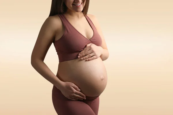 Mladá Těhotná Žena Dotýká Břicho Béžovém Pozadí Detailní Záběr — Stock fotografie