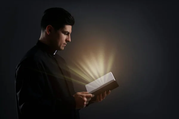 Rahip Elinde Kutsal Işıkla Siyah Arka Planda Ncil Tutuyor — Stok fotoğraf