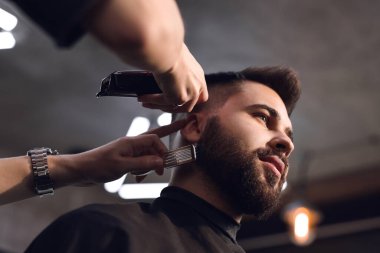 Berber dükkanında müşteriyle çalışan profesyonel kuaför. Düşük açı.