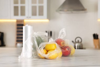 Mutfaktaki beyaz mermer masada farklı taze ürünlerin olduğu plastik torbalar.