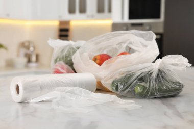 Mutfaktaki beyaz mermer masada farklı taze ürünlerin olduğu plastik torbalar.
