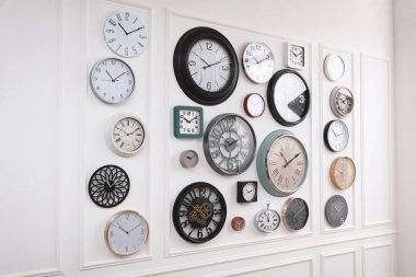 Beyaz duvarda asılı farklı saatlerin koleksiyonu