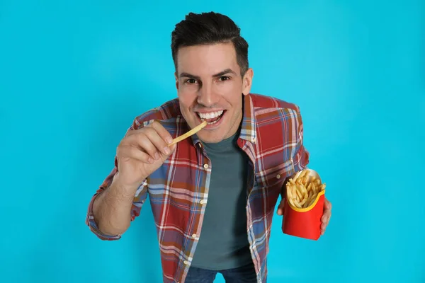 Man Eating French Fries Light Blue Background — Zdjęcie stockowe