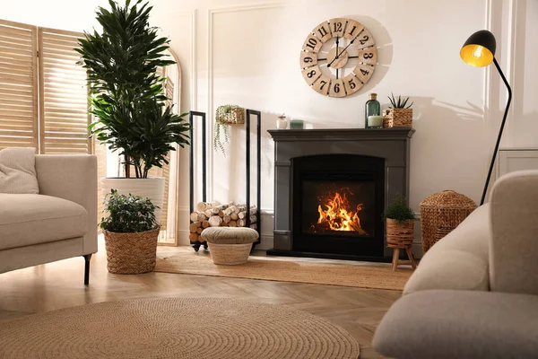 Şık bir oturma odası. İçinde elektrikli şömine, rahat koltuklar ve güzel dekorasyon unsurları var.