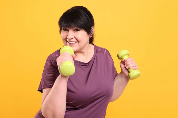 Счастливая Зрелая Женщина Избыточным Весом Делает Упражнения Гантелями Оранжевом Фоне — стоковое фото