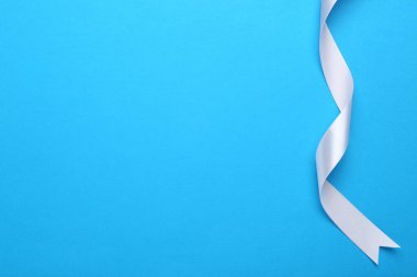 Açık mavi arka planda güzel beyaz kurdele, üst manzara. Metin için boşluk