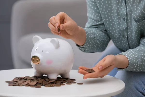 Young Woman Putting Coin Piggy Bank Table Indoors Closeup — Photo