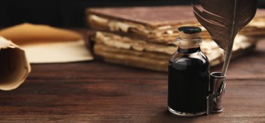 Quill and bottle of ink on wooden table, space for text. Banner design