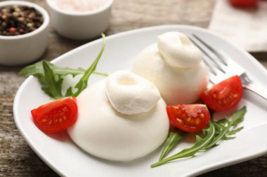 Ahşap masada roka ve domatesli nefis burrata peyniri, yakın plan.