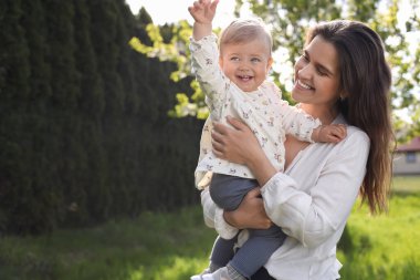 Güneşli bir günde parkta sevimli bebeğiyle mutlu bir anne. Mesaj atmak için uygun bir yer.