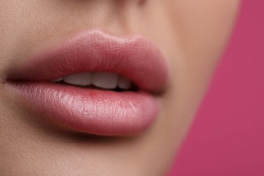 Pembe arka planda güzel dudakları olan genç bir kadın, yakın çekim manzaralı.