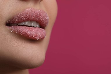 Dudakları şekerle kaplı, pembe arka planda güzel bir kadın, yakın plan. Metin için boşluk