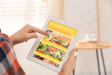Evde yemek siparişi vermek için tablet kullanan bir adam, yakın çekim. Teslimat hizmeti kavramı