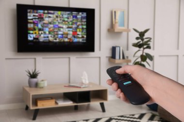 Uzaktan kumandalı kadın evde televizyon izlerken kanal değiştiriyor, kapatıyor