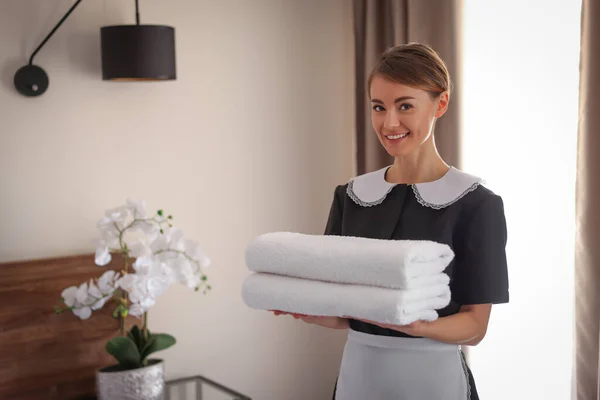 宾馆房间里有一堆堆新鲜毛巾的漂亮女服务员 — 图库照片