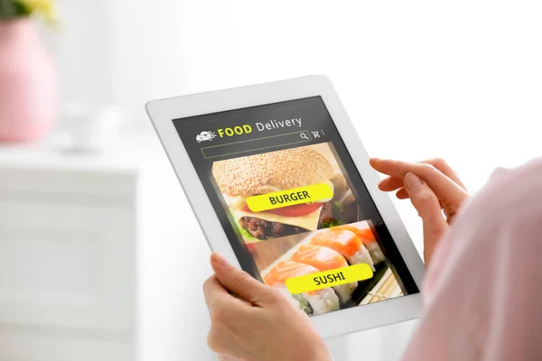 Woman using tablet for ordering food online at home, closeup. Concept of delivery service