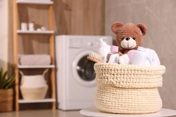 用婴儿用品 浴具和玩具熊编织的篮子放在室内的白桌上 案文的篇幅 — 图库照片