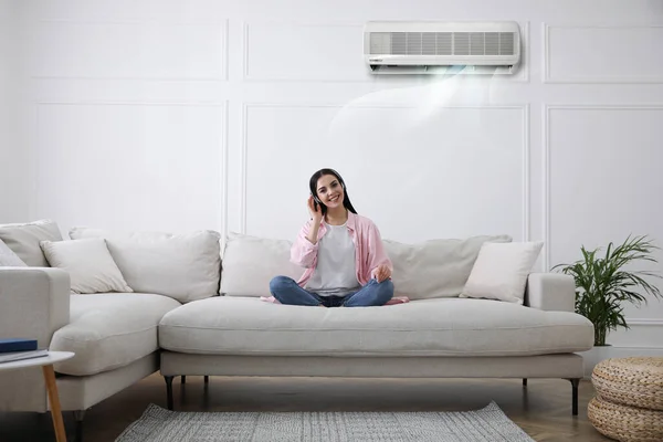 Νεαρή Γυναίκα Αναπαύεται Κάτω Από Κλιματιστικό Λευκό Τοίχο Στο Σπίτι — Φωτογραφία Αρχείου