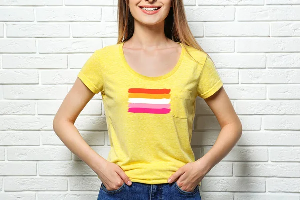 Mladá Žena Žlutém Tričku Lesbickou Vlajkou Zdi Bílých Cihel Koncept — Stock fotografie