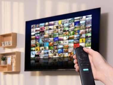 Uzaktan kumandalı kadın evde televizyon izlerken kanal değiştiriyor, kapatıyor
