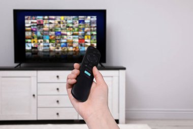 Uzaktan kumandalı kadın evde televizyon izlerken kanal değiştiriyor, kapatıyor