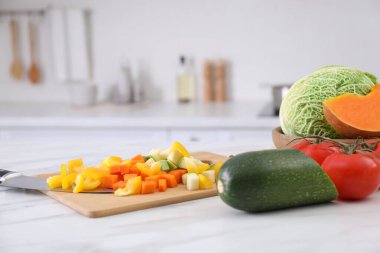 Mutfaktaki beyaz mermer masada farklı çiğ sebzeler.