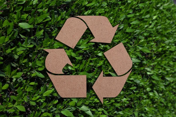 Recycling Symbool Gesneden Uit Kraftpapier Verse Groene Bladeren Achtergrond — Stockfoto