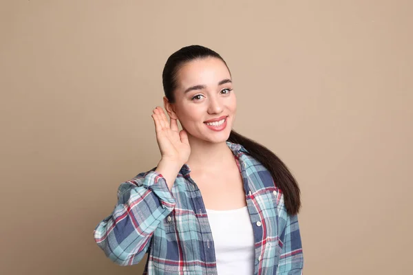 Mujer Joven Mostrando Gesto Mano Oreja Sobre Fondo Beige — Foto de Stock