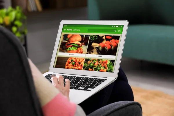 Man using laptop for ordering food online at home, closeup. Concept of delivery service