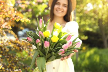 Parkta bir buket lalesi olan güzel genç bir kadın, çiçeklere odaklan.