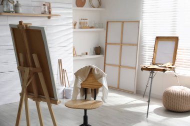 Sanatçının iş yeri ve geniş pencerenin yanında katlanabilir ahşap sehpası olan modern bir stüdyo.