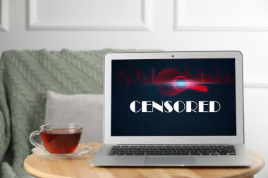 Laptop with censorship sign on wooden table indoors
