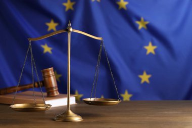 Adalet terazileri, hakimin tokmağı ve kitabı Avrupa Birliği bayrağına karşı ahşap masa üzerinde