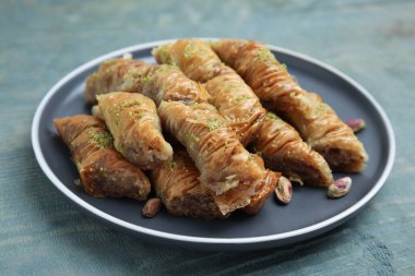 Açık mavi ahşap masada fıstıklı enfes baklava, yakın plan.