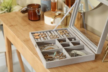 Zarif mücevher kutusu, güzel bijouterie, lüks parfüm şişeleri ve oda odasındaki ahşap masada şık aksesuarlar.