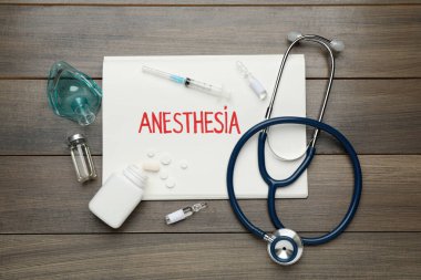 Tahta masada anestezi ve uyuşturucu içeren düz bir kompozisyon.