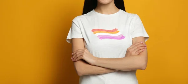 オレンジ色の背景にレズビアンの旗が付いた白いTシャツを着た若い女性 バナーデザイン Lgbtの概念 — ストック写真