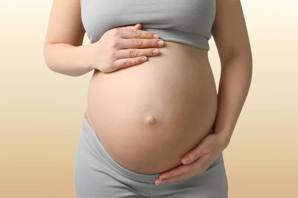 Young Pregnant Woman Touching Her Belly Beige Background Closeup — Photo