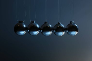 Newton 'un gri arka plandaki beşiği, yakın plan. Enerji korunumunun fizik yasası
