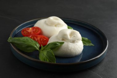 Lezzetli burrata peyniri fesleğenli ve domatesli siyah masa